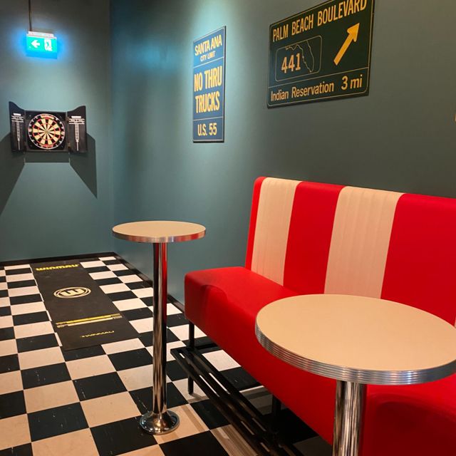 Sitteplasser med små bord ved dartboard